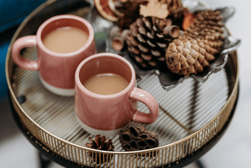 What self-care really mean - two mugs of team on a side table next to pine cones